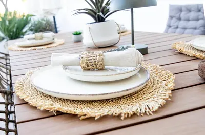 a table with white plates and rattan placemats at Nostalgia Suites in Faliraki