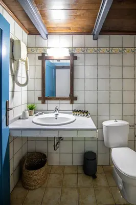a bathroom with a sink and a toilet and a mirror at Nostalgia Suites in Faliraki