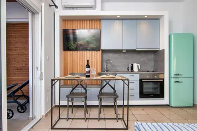 a kitchen with a table with two chairs and a bottle of wine at Nostalgia Suites in Faliraki