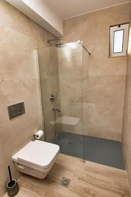 a bathroom with a toilet and a glass shower at Nostalgia Suites in Faliraki