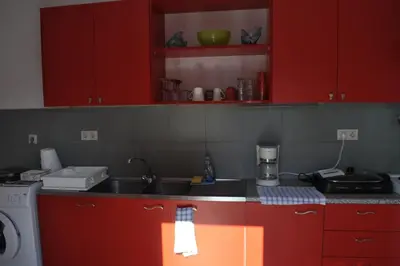 a kitchen with red cabinets and a sink at Park House -beside the Medieval Town of Rhodes-free parking in Rhodes Town