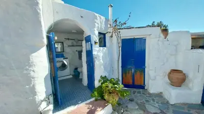 a white building with blue doors and a vase at Clive and Bifi's house in Lachania