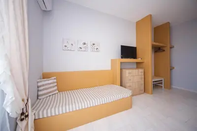 a small bedroom with a yellow bed and a cabinet at Sunset Apartments in Archangelos