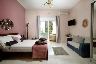 a bedroom with a bed and a couch and a mirror at Sunset Apartments in Archangelos