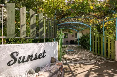 a gate to a garden with a sign that reads sunset at Sunset Apartments in Archangelos