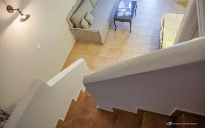 a white stairway with a couch and a chair at Iapetos Village in Symi