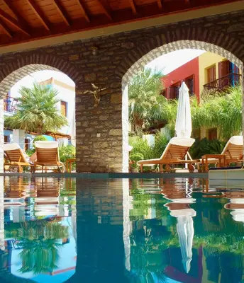 a pool at a resort with chairs and a umbrella at Iapetos Village in Symi