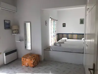 a white bedroom with a bed and a window at Villa George in Apolakkiá
