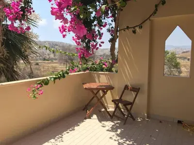 a table and a chair on a balcony with flowers at Villa George in Apolakkiá