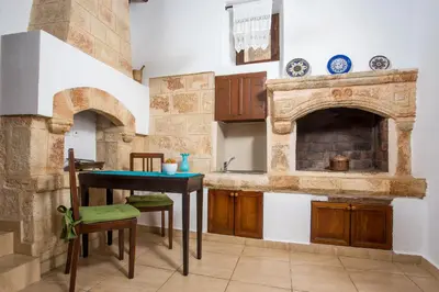 a kitchen with a table and a fireplace at CasaLindos Festa in Líndos