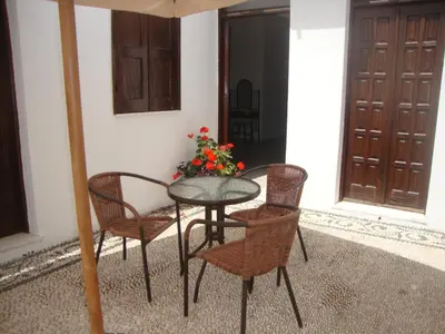 a table and chairs with a flower vase on a porch at Sarris Studios & Apartments in Líndos