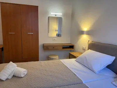 a bedroom with a bed and a cabinet and a mirror at Sarris Studios & Apartments in Líndos