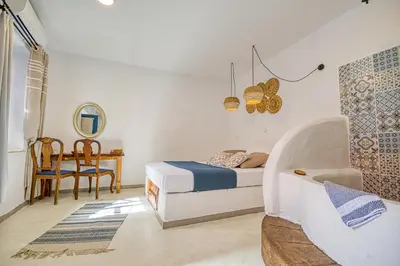a bedroom with a bed and a table and a chair at Mascot Garden Rooms in Rhodes Town