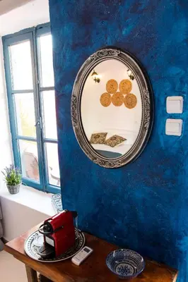 a mirror on a blue wall next to a table at Mascot Garden Rooms in Rhodes Town