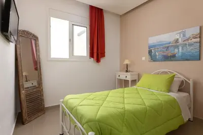a bedroom with a green bed and a mirror at Villa Kivotos in Lardos