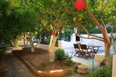 a patio with a table and chairs under trees at Romantic rooms with stunning sea view in Rhodes Town