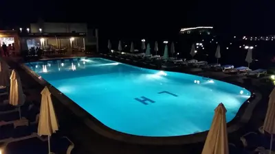 a large swimming pool at night with umbrellas at LINDOS HORIZON in Líndos
