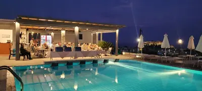 a group of people sitting at a table by a pool at LINDOS HORIZON in Líndos