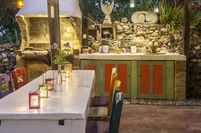 a table and chairs in front of a stone wall at Oliveyard Stone Built House- with pool non chlorin in Koskinou