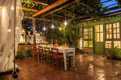 a white table and chairs in a room with plants at Oliveyard Stone Built House- with pool non chlorin in Koskinou