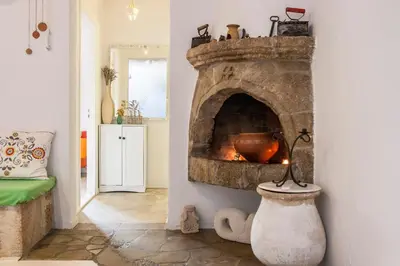 a kitchen with a stone fireplace in a room at Oliveyard Stone Built House- with pool non chlorin in Koskinou