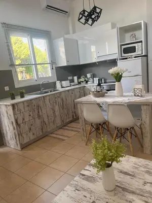 a kitchen with white cabinets and a table with chairs at La Casa de Tsampika in Koskinou