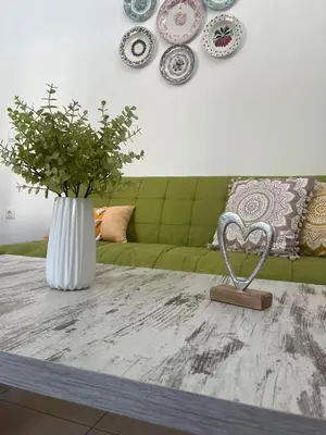 a living room with a table with a vase with a plant at La Casa de Tsampika in Koskinou
