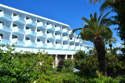 a building with a palm tree in front of it at Blue Horizon in Ialyssos