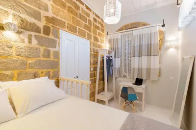 a brick walled bedroom with a bed and a chair at A33 Rhodes Old Town House in Rhodes Town