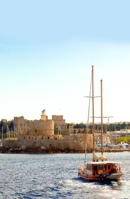 a boat in the water with a city in the background at A33 Rhodes Old Town House in Rhodes Town