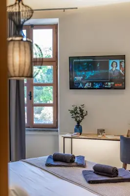 a bedroom with a tv on the wall and two towels at Casa Poli Suites in Rhodes Town