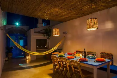 a dining room with a table with chairs and a hammock at Villa Kefi in Koskinou