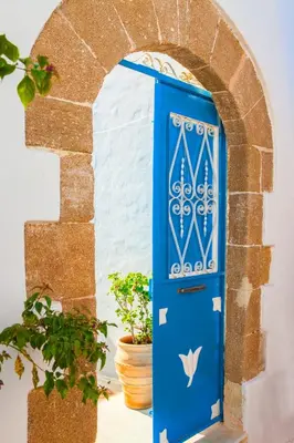 a blue door with a gate and a potted plant at Villa Kefi in Koskinou