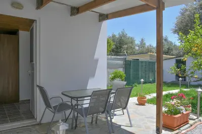a patio with a table and chairs in a yard at The Olive Garden House in Haraki