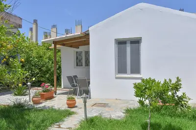 a white house with chairs and plants in a yard at The Olive Garden House in Haraki