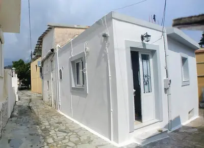 a white building with a door on a street at BEAUTIFUL HOUSE OF PSINTHOS in Psinthos