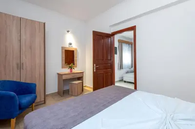 a bedroom with a bed and a blue chair at Paradise Garden in Kolimbia