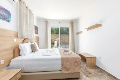 a white bedroom with a bed and a window at Paradise Garden in Kolimbia