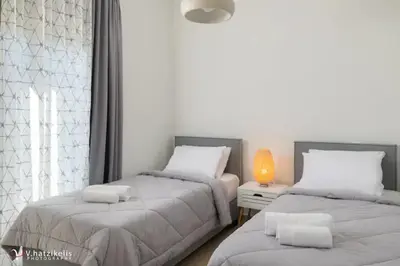 a bedroom with two beds and a table with a lamp at Terpsis Pool Villa in Rhodes Town