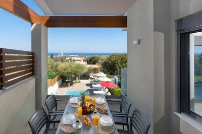 a table on a balcony with a view of the ocean at Terpsis Pool Villa in Rhodes Town