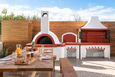 a patio with a table and a pizza oven at Ifigeneia Villa in Afantou