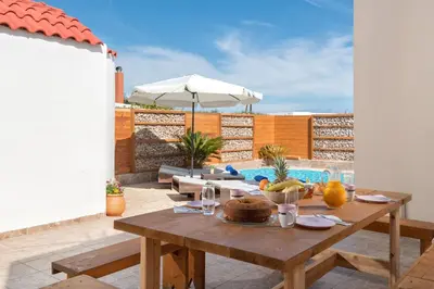 a table with food on it on a patio at Ifigeneia Villa in Afantou