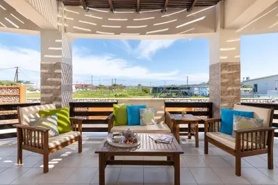 a patio with chairs and tables on a roof at Ifigeneia Villa in Afantou