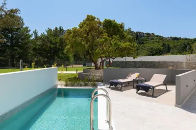 a pool with two chairs and a table on a patio at Atalanti Boutique Hotel - Adults Only in Faliraki