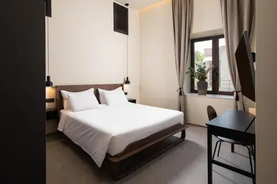 a bedroom with a bed and a desk and a window at Villa Fluvian in Rhodes Town
