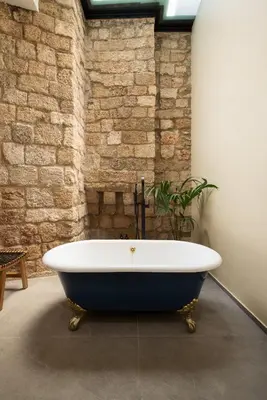 a bath tub in a room with a brick wall at Villa Fluvian in Rhodes Town