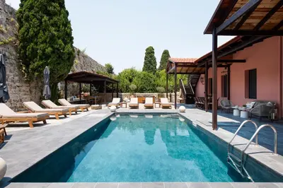 a pool with lounge chairs and a house at Villa Fluvian in Rhodes Town