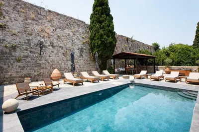 a swimming pool with chaise lounge chairs and a patio at Villa Fluvian in Rhodes Town