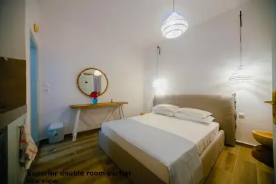 a bedroom with a white bed and a mirror at St. Paul's Bay View Suites in Líndos