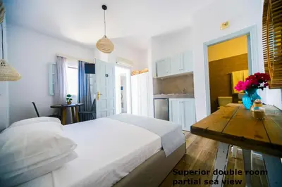 a white bedroom with a bed and a wooden table at St. Paul's Bay View Suites in Líndos